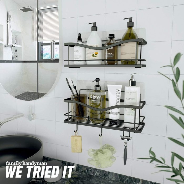 Black wire shelves hold various toiletries and grooming items in a modern bathroom, alongside a sink and a mirror reflecting a shower area.
