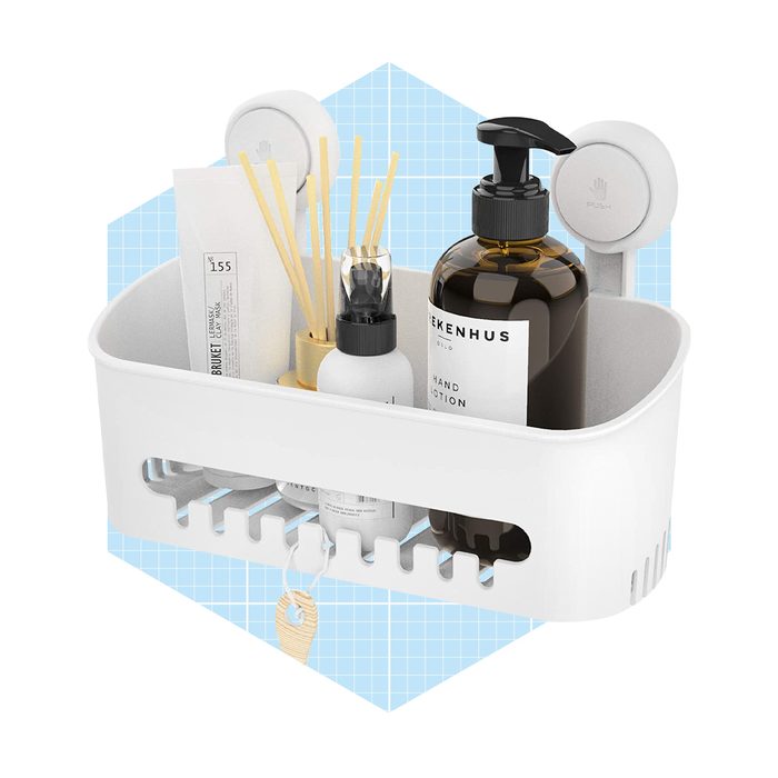 A white storage basket holds various hygiene products, including lotions and reed diffusers, mounted against a light blue patterned background.