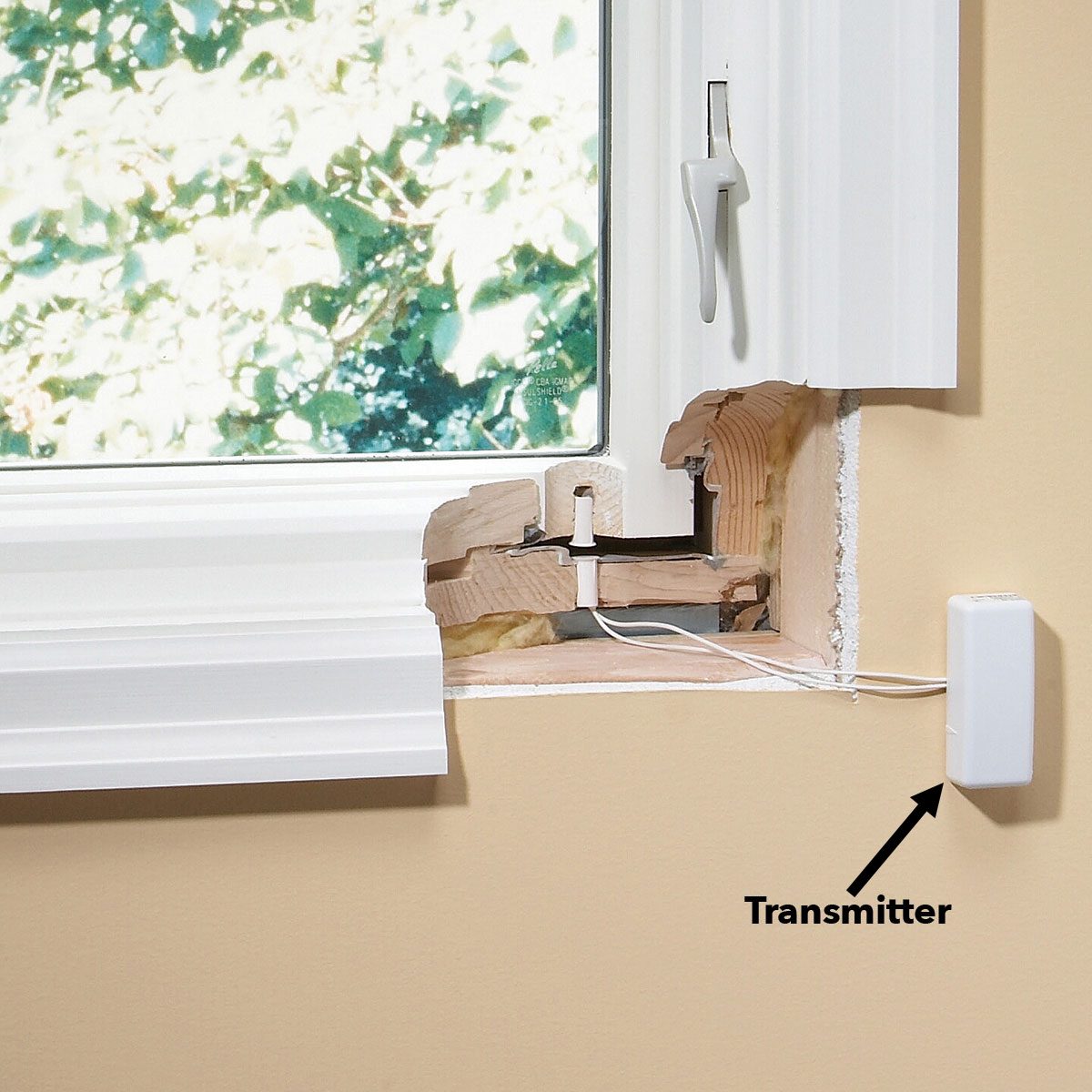A window frame shows exposed wood and hardware, with a transmitter attached to the wall, surrounded by a light-colored wall and a blurred outdoor view.