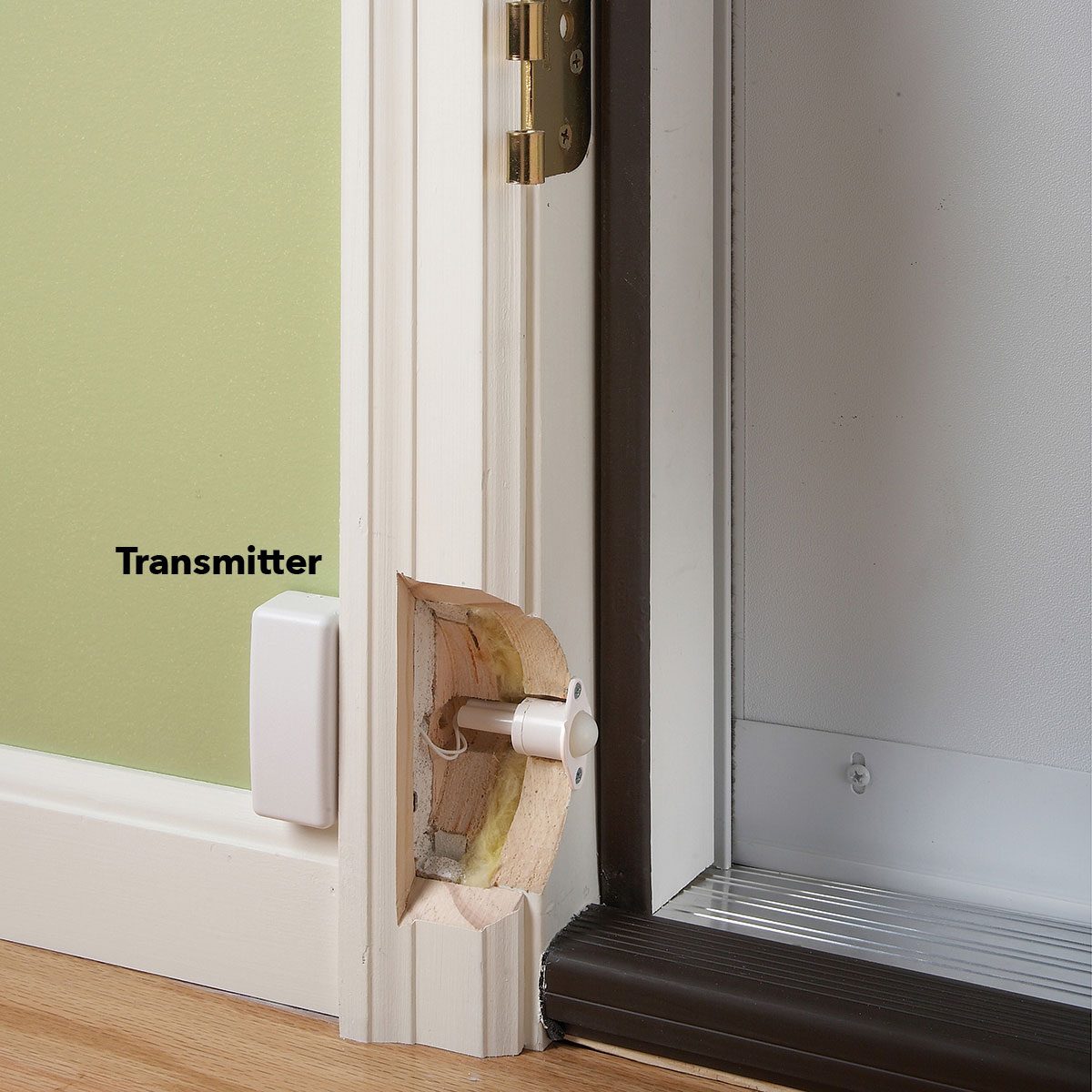 A transmitter is installed at a door frame; a round component extends from an embedded socket, contributing to a home security system.