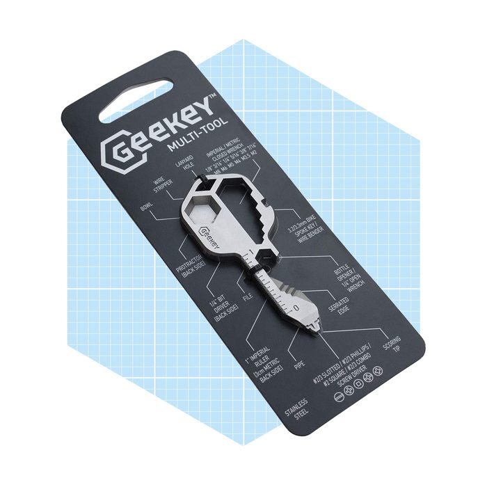 A stainless steel multi-tool key sits on a black card, showcasing various functions like bottle opener and screwdriver, against a blue grid background.