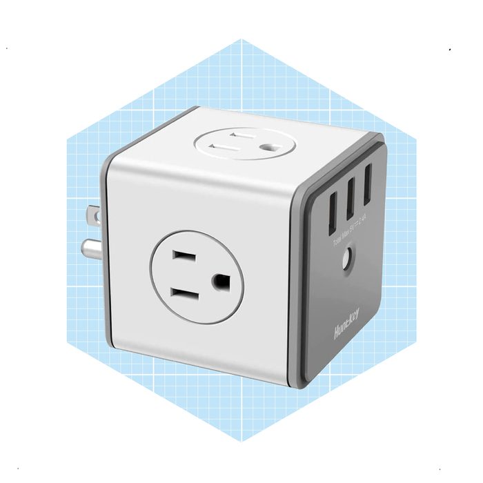A compact power adapter with multiple outlets connects devices, set against a light blue grid background, providing efficient charging options.