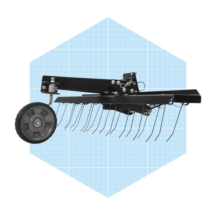 A black lawn dethatcher with a wheel and metal tines is positioned against a light blue, grid-patterned background.