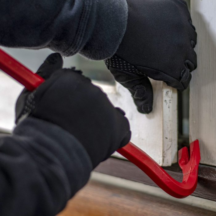 Thief with a bar of iron in the hand to open a door