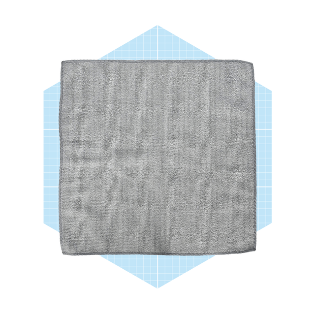 A gray dishcloth lies flat, showcasing its textured surface, on a light blue hexagonal background with a grid pattern.