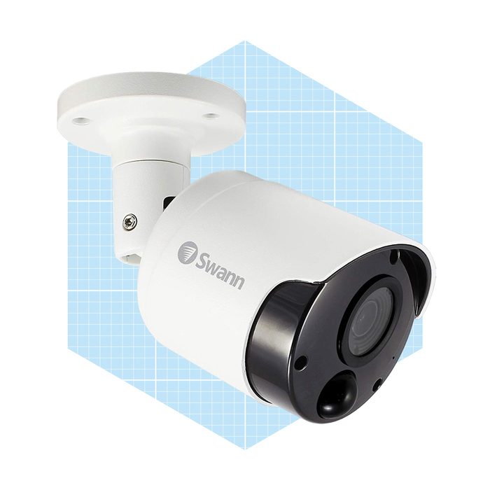 A security camera is mounted on a wall, designed to capture video footage. It features a white body with a black lens, against a blue grid backdrop.