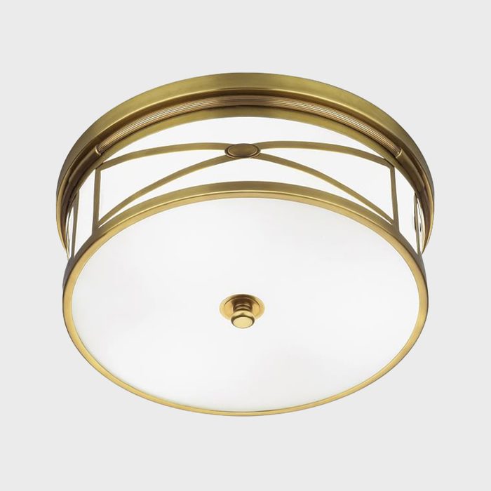 A round ceiling light fixture illuminates a space, featuring a brass frame and a frosted glass shade, enhancing the interior's elegance.