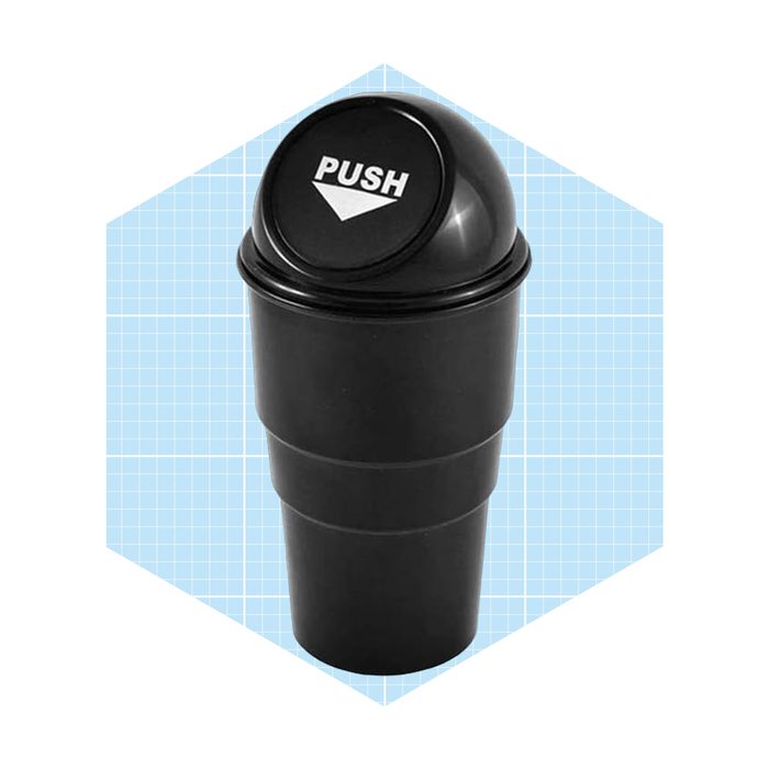 A black, two-part cylindrical container with a push-top lid sits against a light blue graph-patterned background, suggesting it's for disposing of waste.