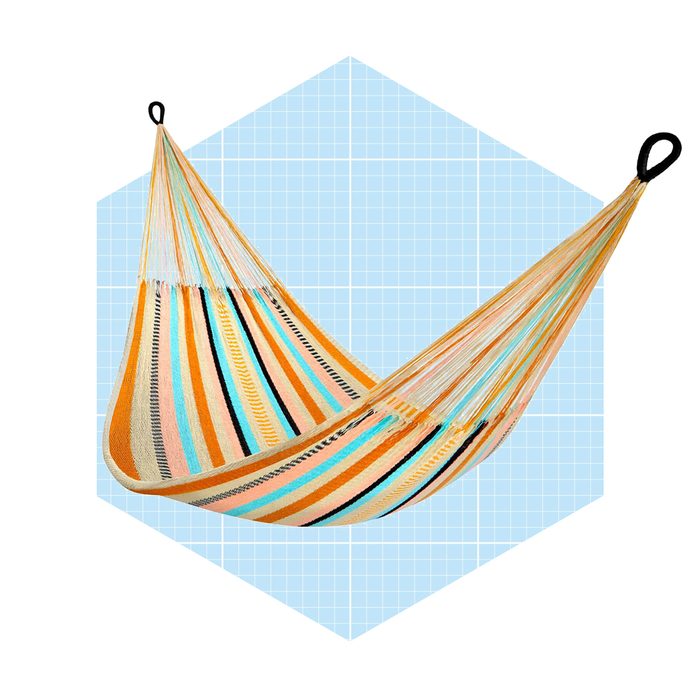 A colorful hammock hangs from two loops, swaying gently against a light blue, grid-patterned background, inviting relaxation in a cozy setting.