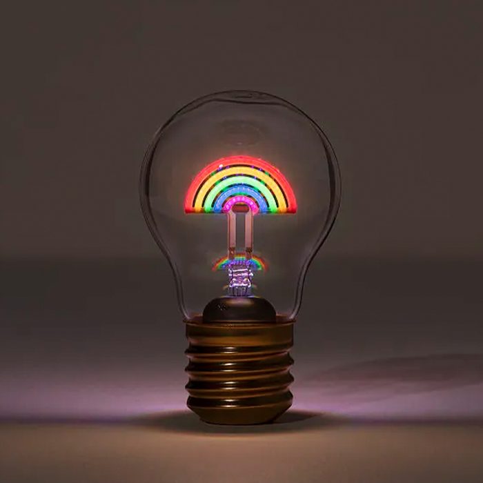 A light bulb features a colorful rainbow inside, illuminated against a dark background, creating a vibrant, decorative display.