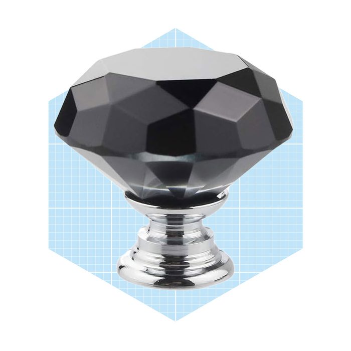 A faceted black crystal knob sits on a shiny silver base, showcasing its geometric design against a light blue grid background.