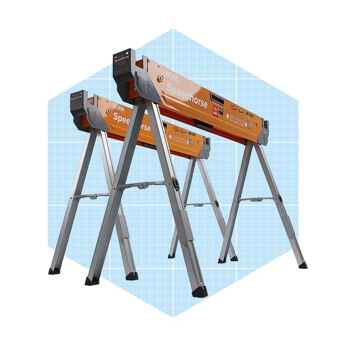 A pair of orange adjustable sawhorses stands upright, providing support for construction tasks, set against a light blue grid background.