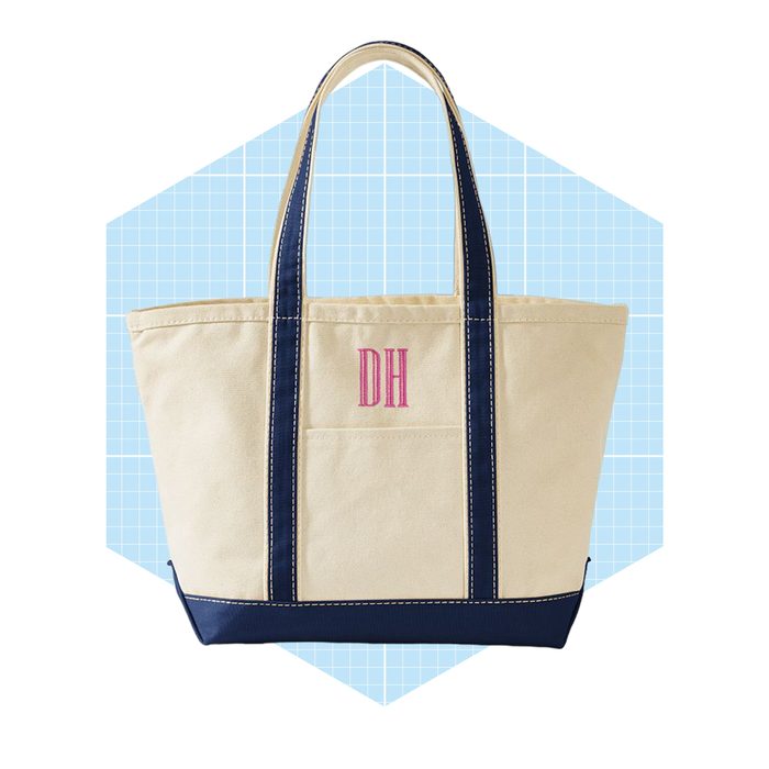 A beige tote bag with navy accents displays the initials 